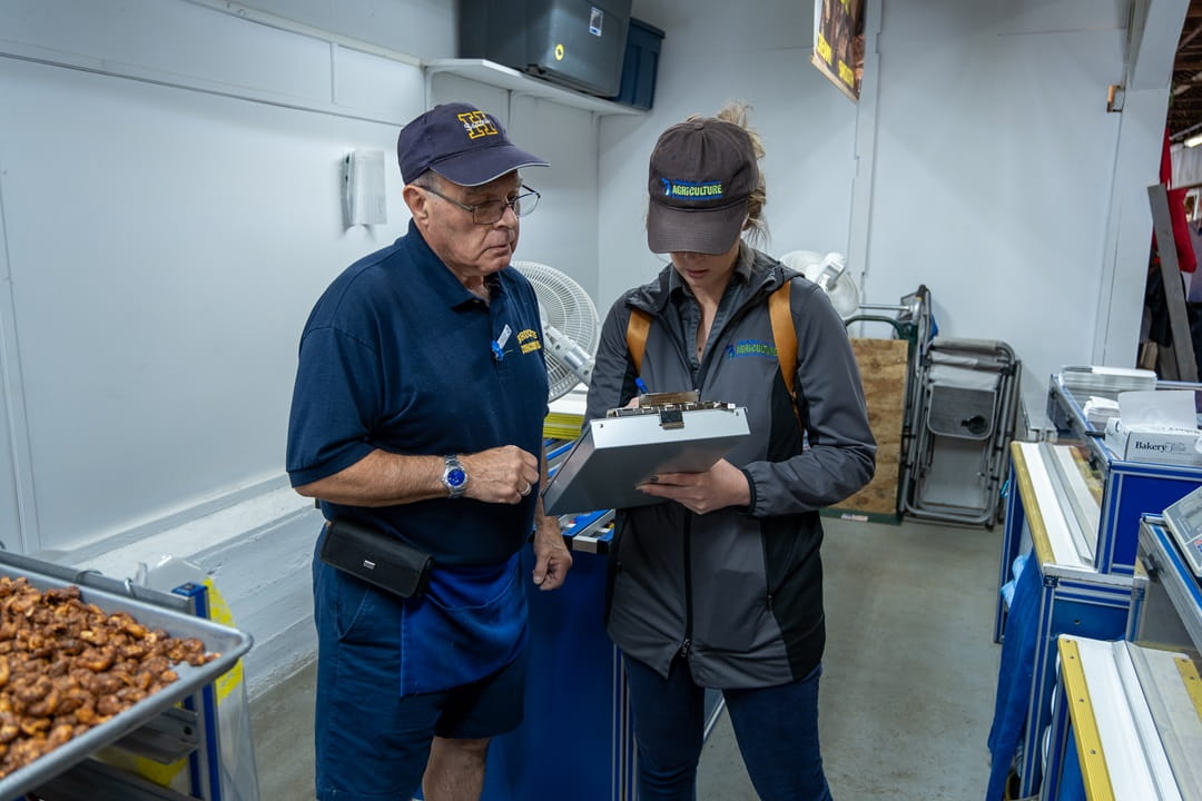 Food inspector staff in the prep area of a food establishment, checking items off a checklist.