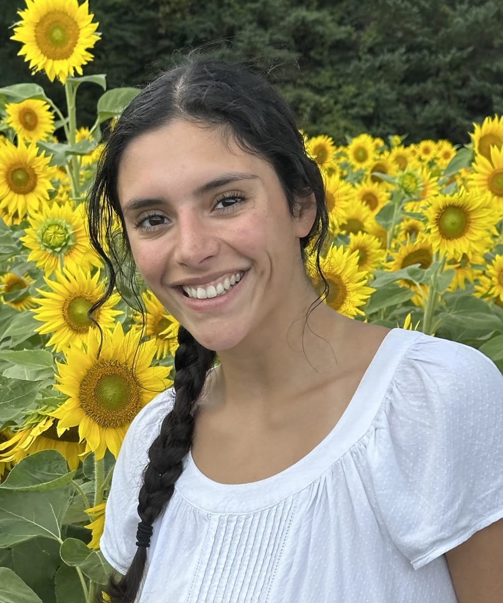 Headshot of Elena in a field of sunflowers