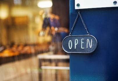 A restaurant is opening and there is a sign hanging in front that says "Open"