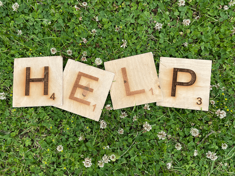 The word 'help' spelled with scrabble tiles