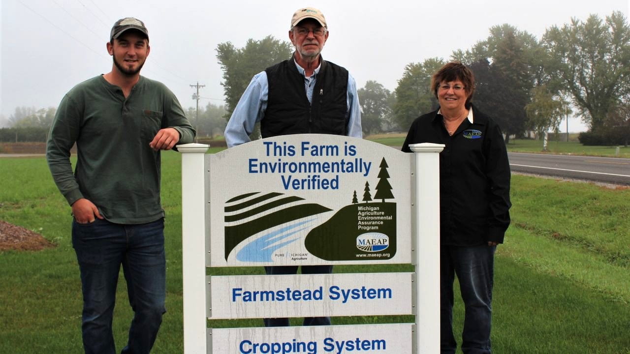 Three people standing in front of a MAEAP Verification sign for a farmstead system