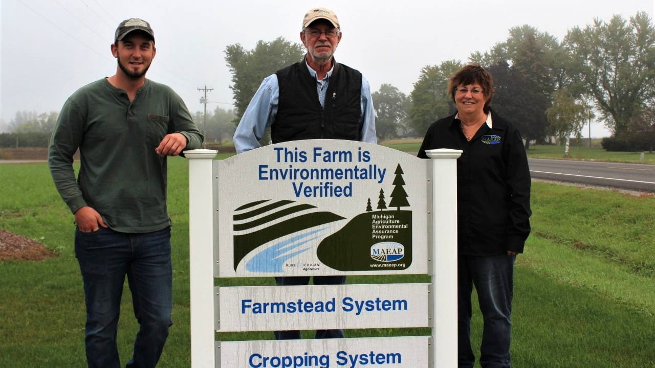Three people standing in front of a MAEAP Verification sign for a farmstead system