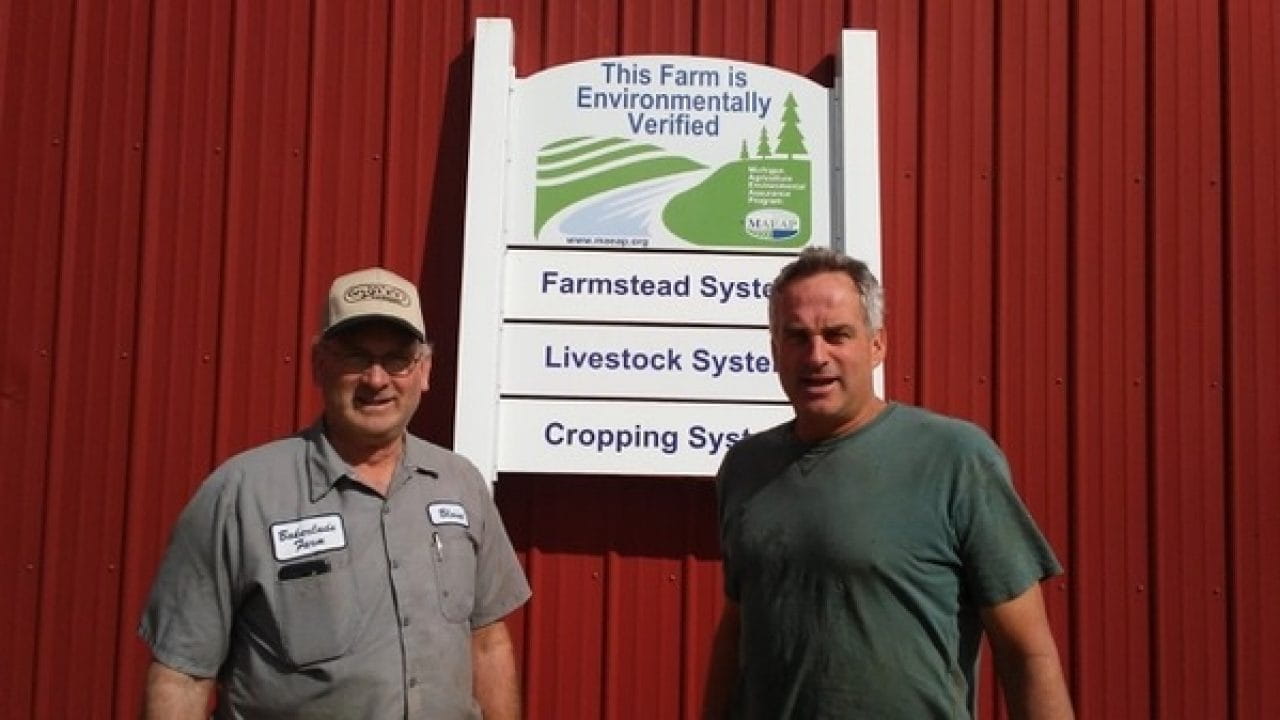 two men in front of a barn with a MAEAP verification sign: farmstead, livestock and cropping systems verified