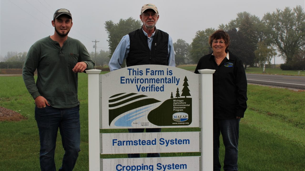 Stotler family standing behind a farmstead system and cropping system verified sign