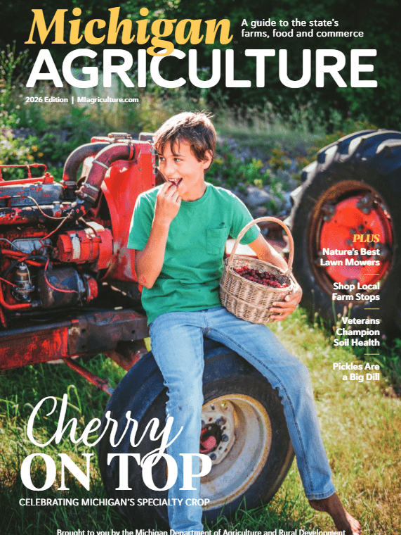 Cover of Michigan Agriculture magazine: a boy eating fruit while sitting on a tractor