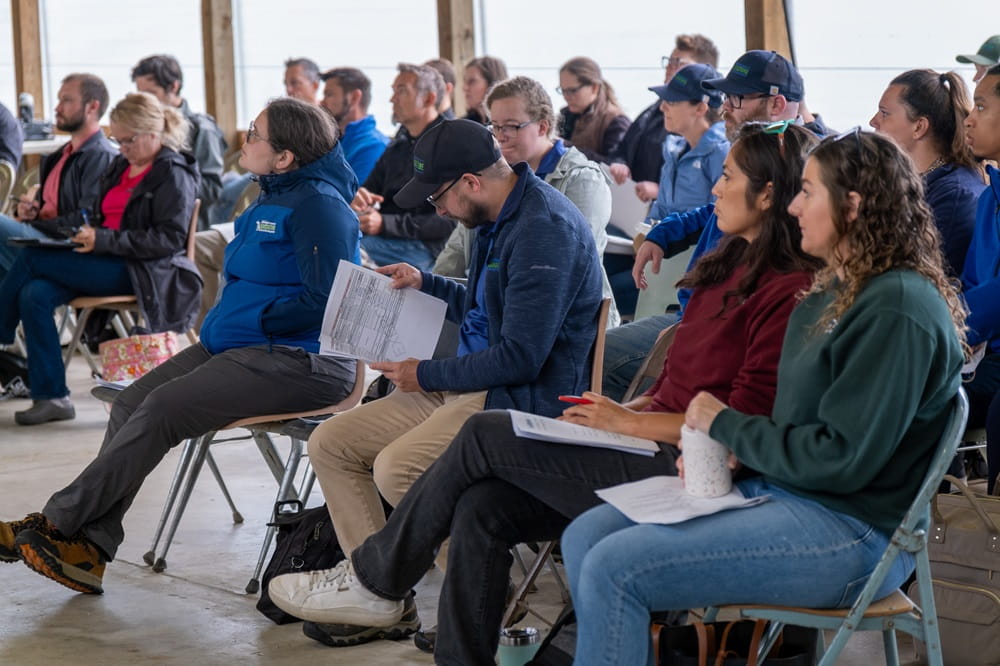A group of people sitting in an outdoor lecture-style classroom.