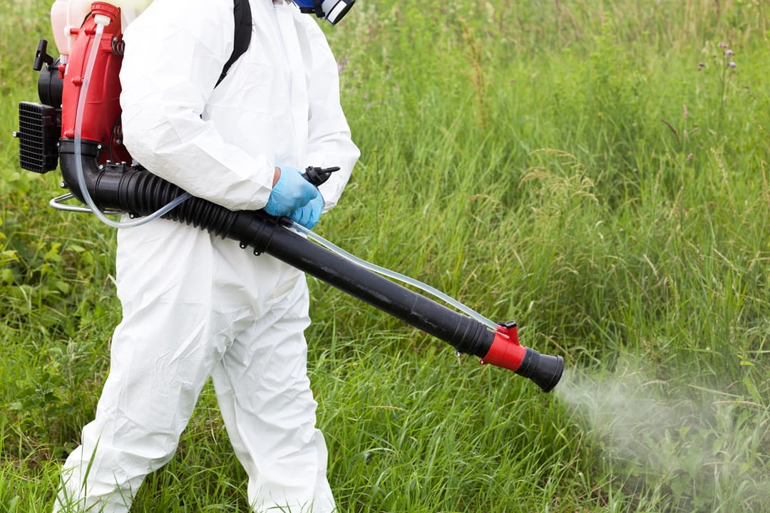 Pesticide applicator wearing PPE while spraying a chemical