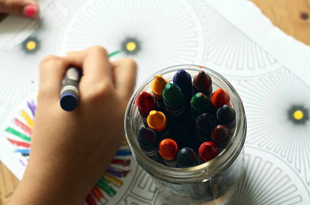 Close up of a child drawing with crayons 