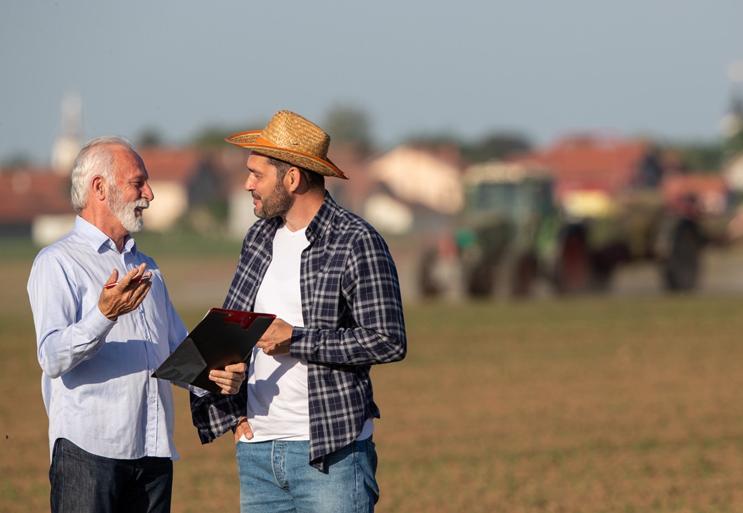 A farmer and a regulator filling out a form outside in a field.