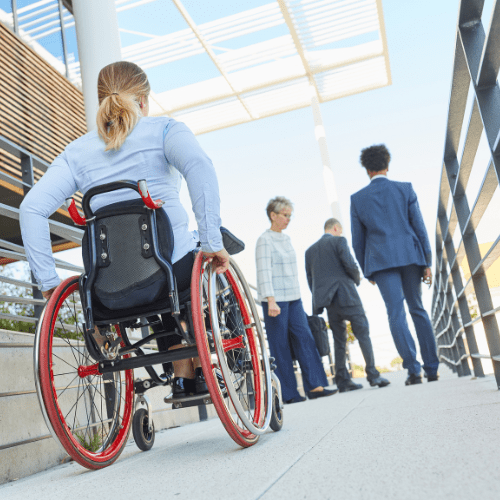 A woman using a wheelchair climbs a ramp behind several people.