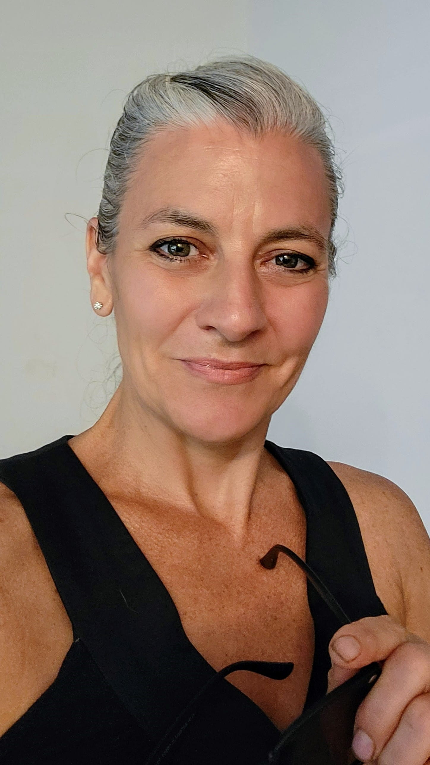 Image of a woman with gray hair pulled back and a black tank top