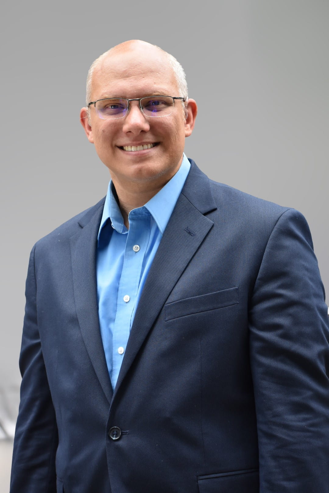 Image of a man with short white hair in a dark blue suit with a light blue shirt