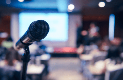 Photo of a microphone with a blurry audience in the background