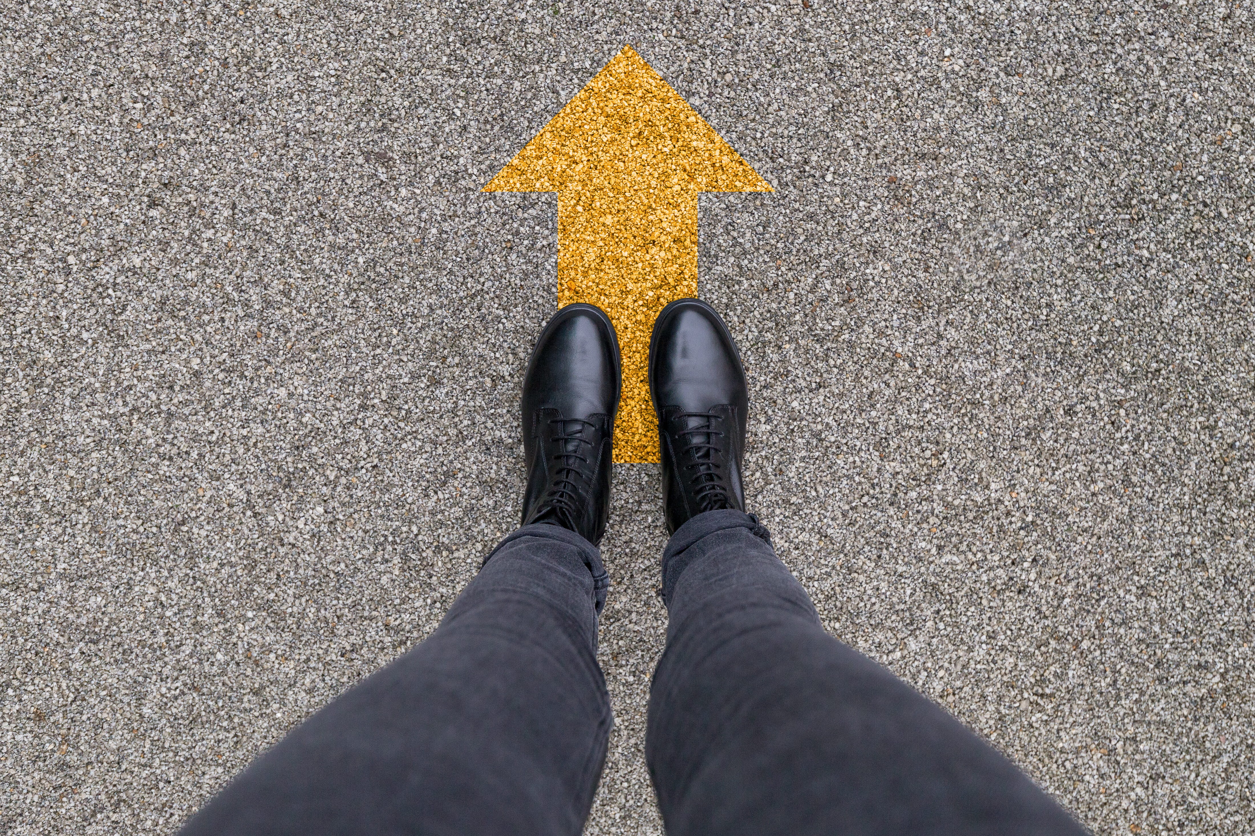 black shoes standing on an yellow arrow