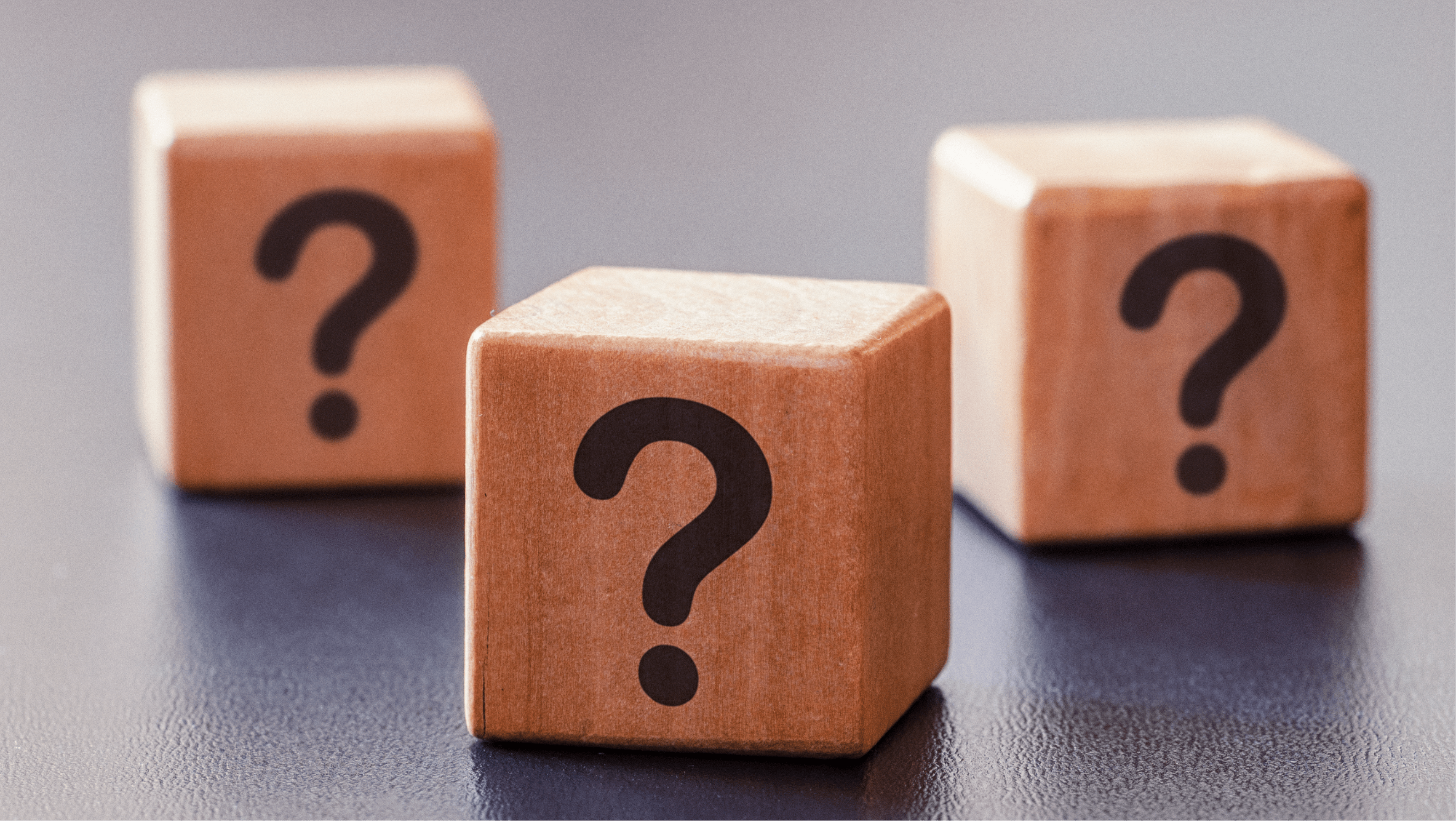 Three wooden blocks with questions marks on a table.