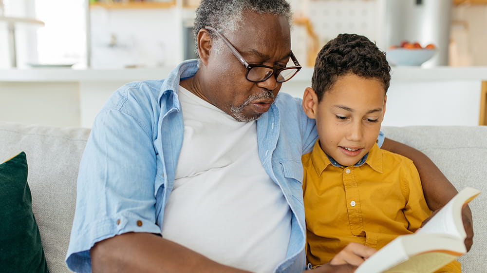 African American grandfather reading a book with his grandson.
