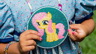 Funding icon displaying an image of a child holding a completed beadwork craft
