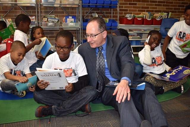 adult and child reading a book in classroom