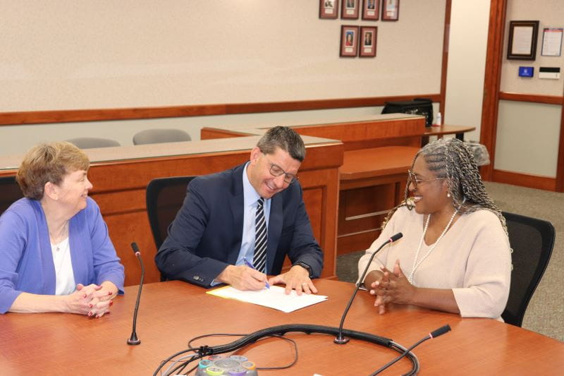 Three people sitting at board table