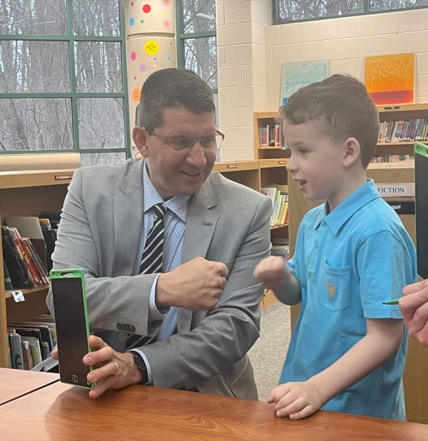 Adult male bumping fists with student