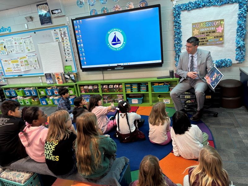 Adult male reading in front of a classroom