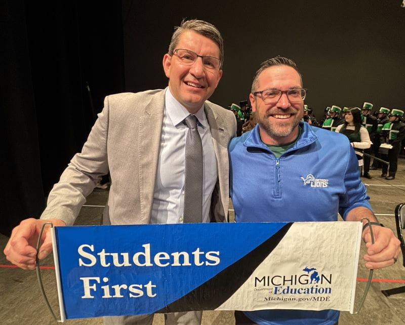 two men holding banner that reads students first