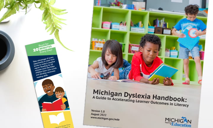 White desk surface with the Michigan Dyslexia Handbook and a Reading Bookmark on it.