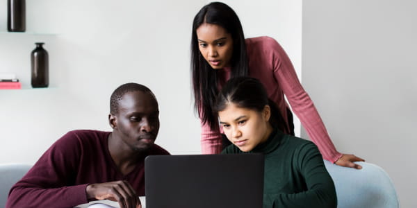 Diverse group of adults gathered around a laptop watching training.