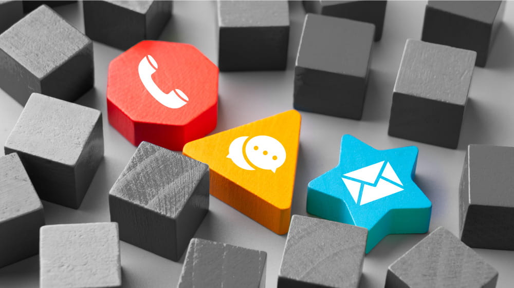 Wooden blocks with icons representing phone, text, and email.