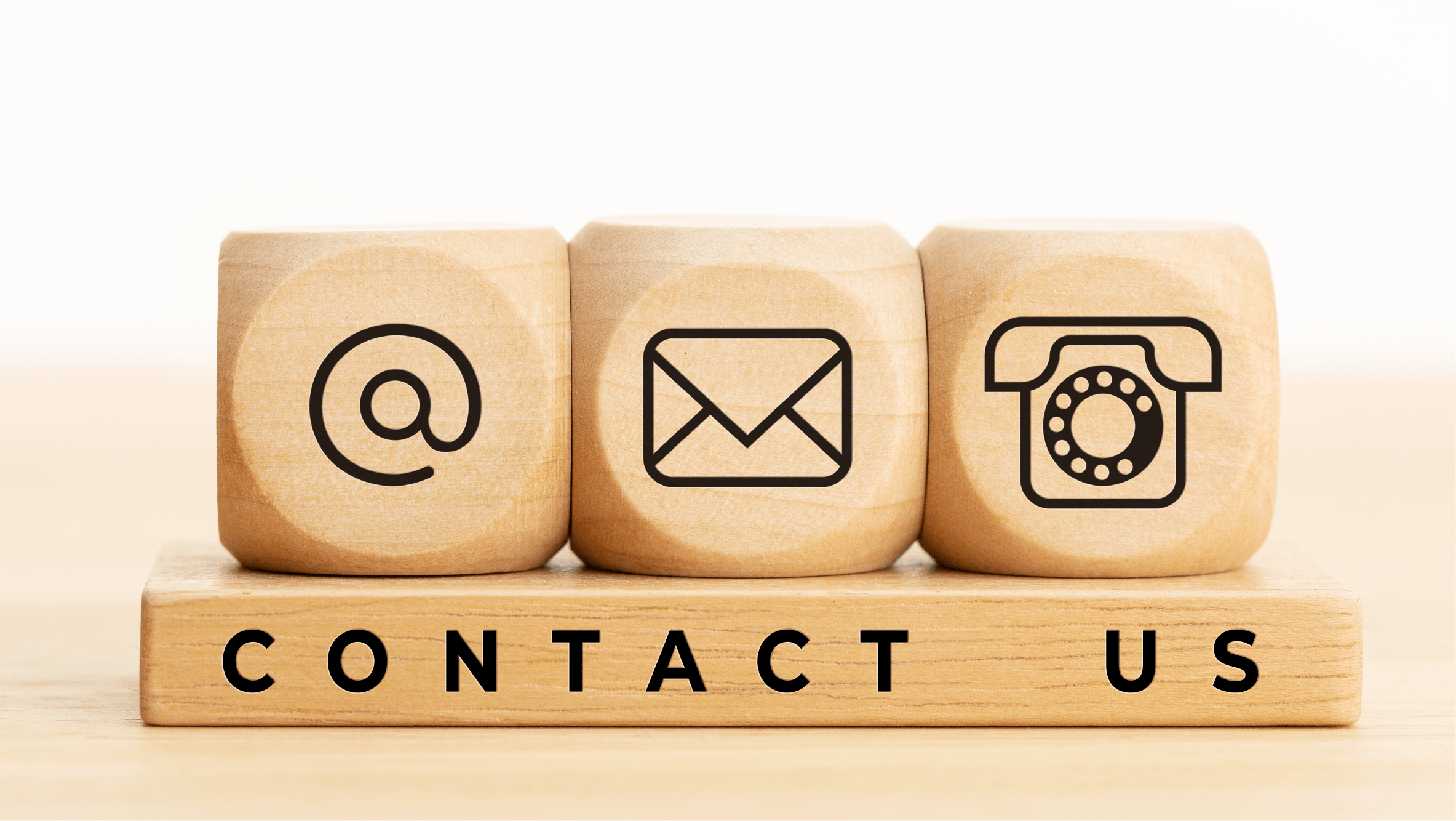 Wooden blocks with icons for email, mail, and telephone stacked on block with "Contact Us."