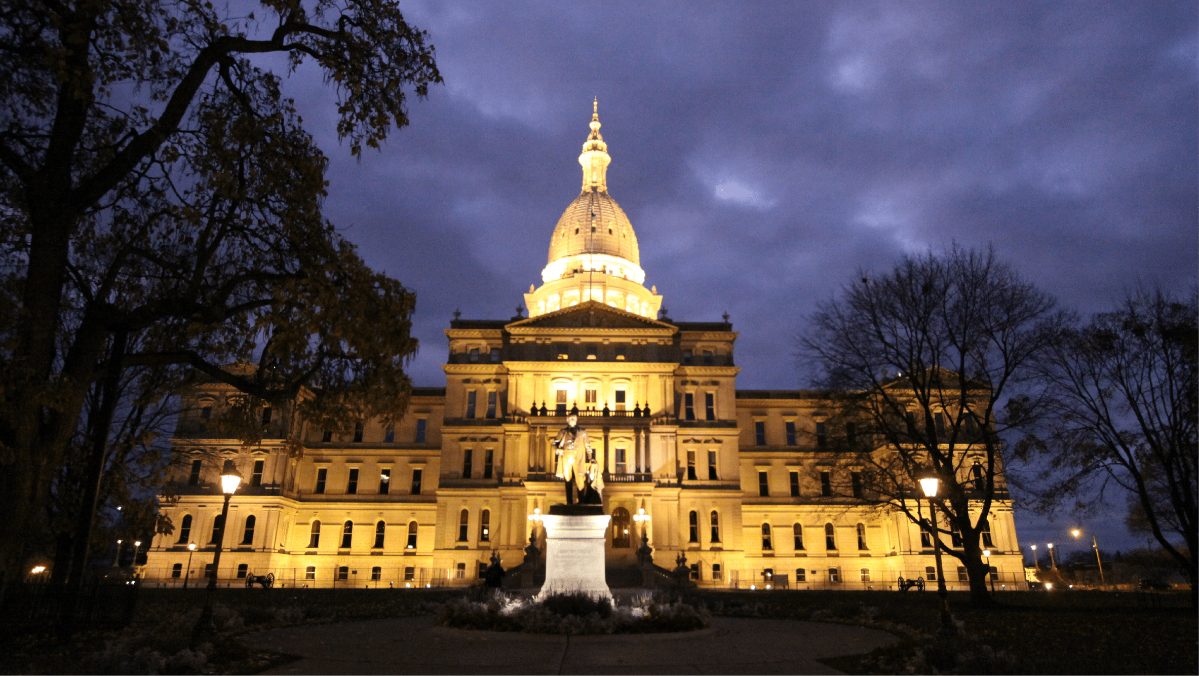 Front view of the Michigan Capitol Building at dusk with cloudy skies.