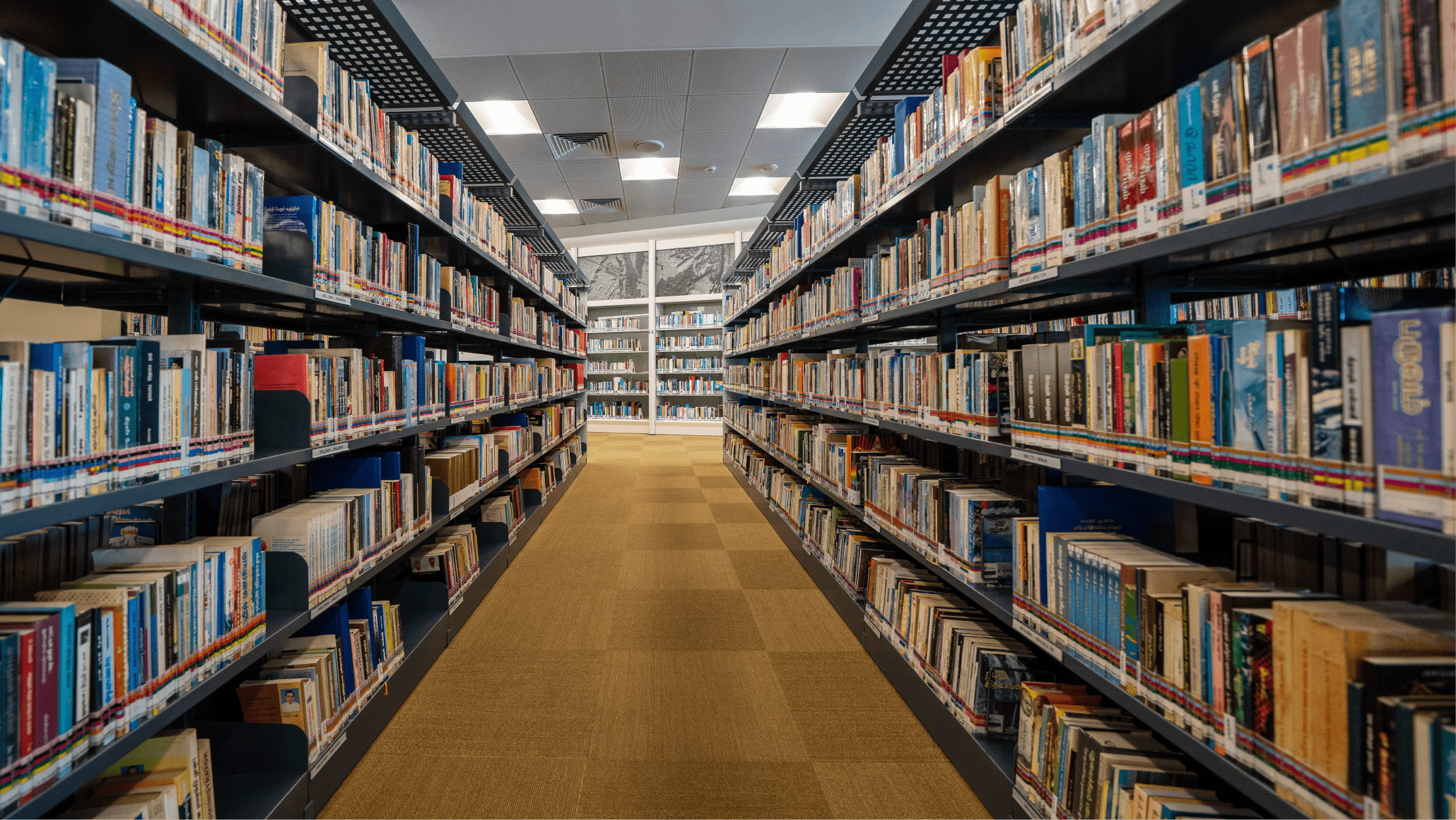 Aisle in a library with filled bookshelves on either side.