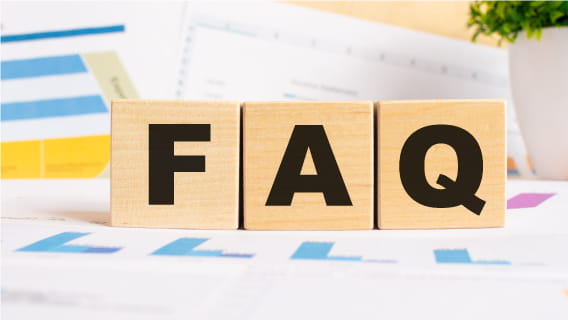 Wooden blocks with "FAQ" on them surrounded by financial papers.