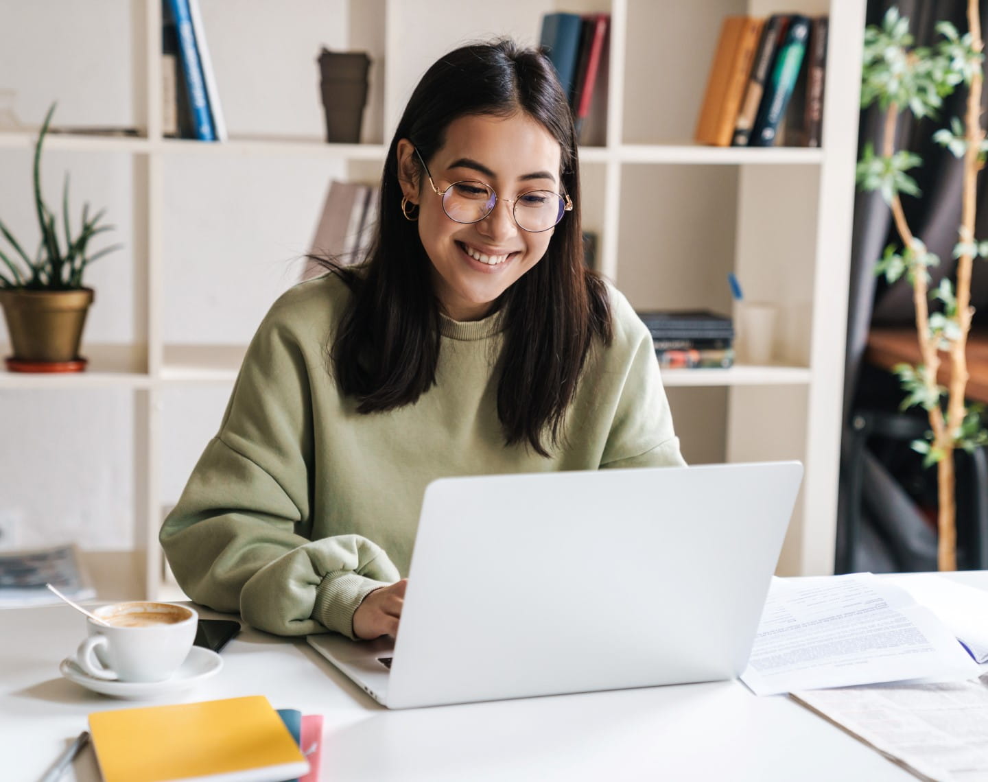 A female wearing glasses works at a laptop computer at home