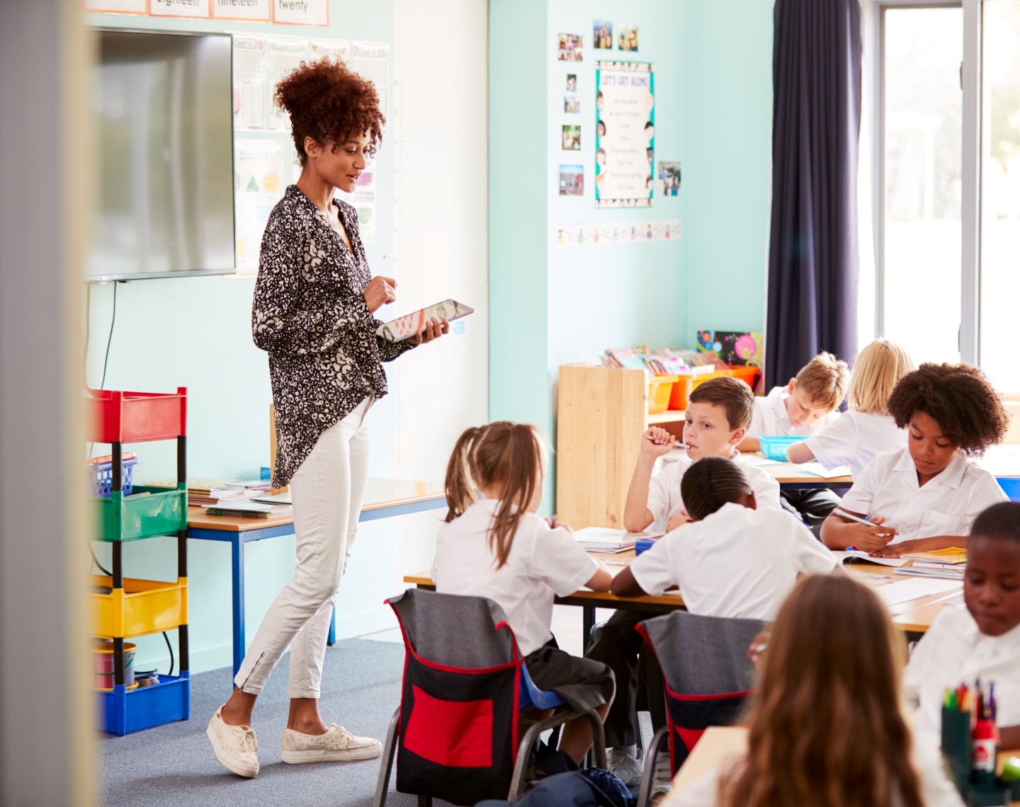 A female teacher stands in front of a class of elementary students wearing uniforms