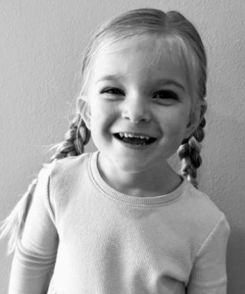 Adley, a young girl wearing braided pigtails, smiles at the camera.