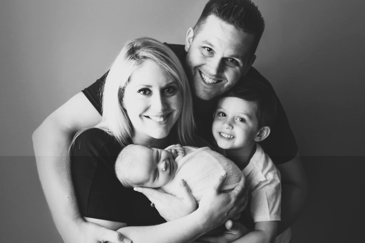A family photo, featuring a father, young boy, and mother holding a baby.