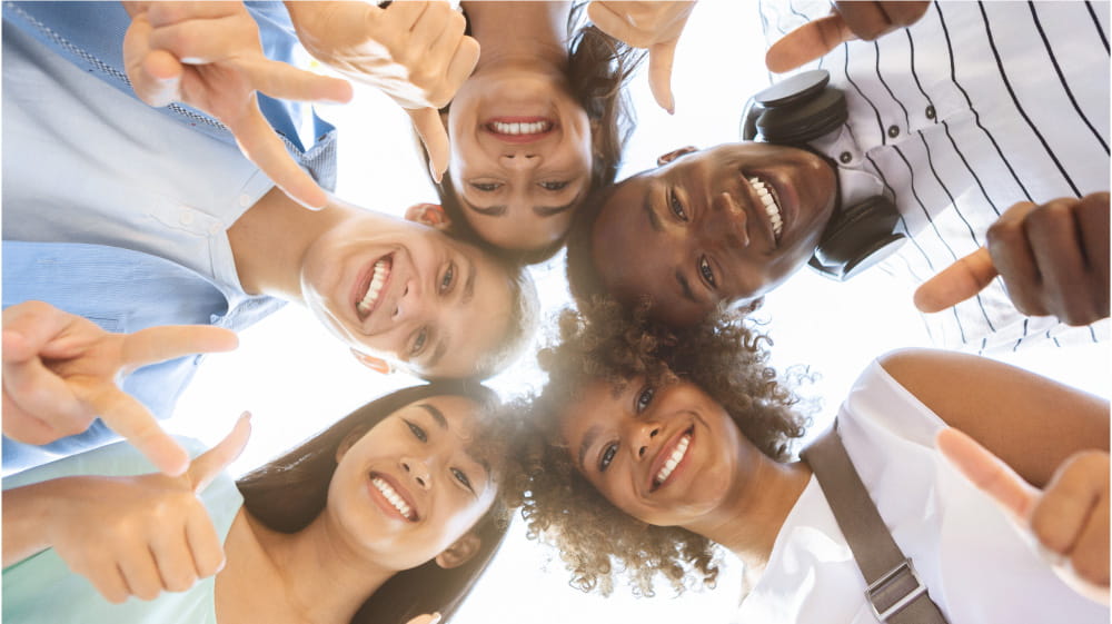 Five students with heads together smiling down at the camera