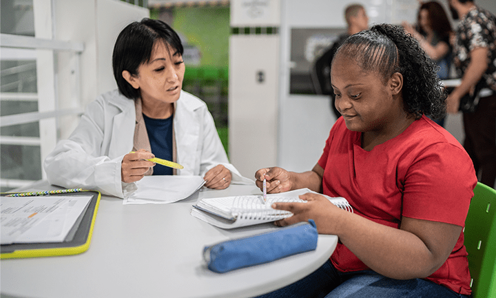 High school student working with a teacher in a lab setting.