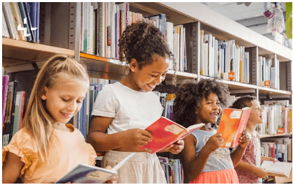 Three elementary girls reading books in the library