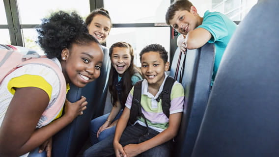 5 pre teens smiling on the bus