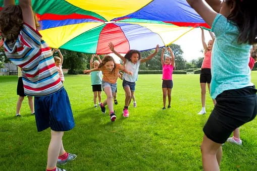 Children in a circle playing under a parachute