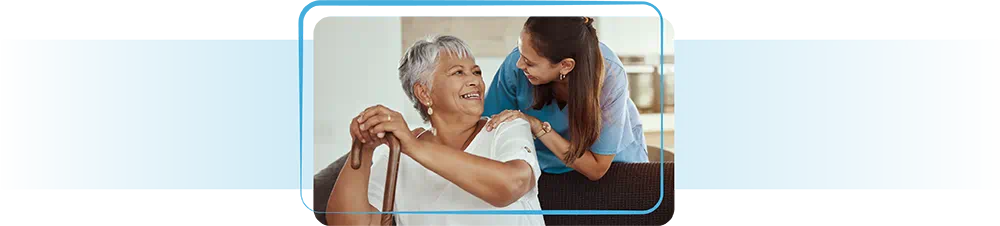 Younger woman leaning over and talking to an older woman with a cane.