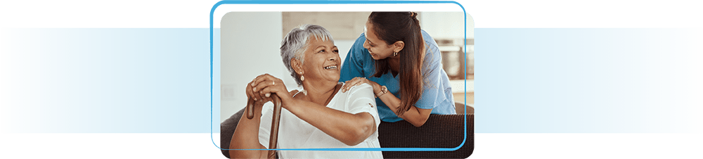Younger woman leaning over and talking to an older woman with a cane.