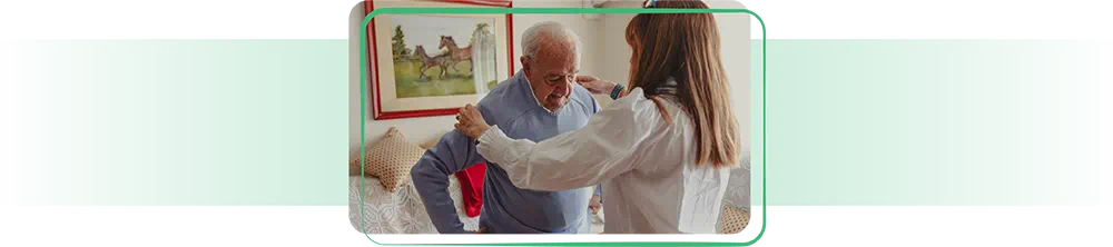 Assisted living worker helping elderly man get dressed.