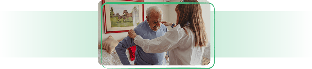Assisted living worker helping elderly man get dressed.