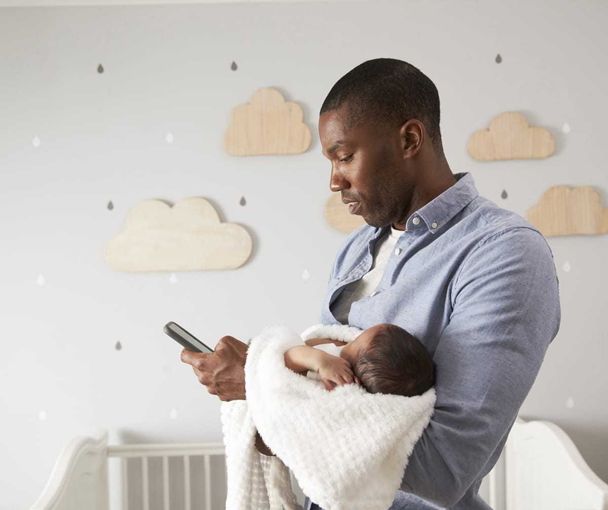 young father holding infant and cellphone