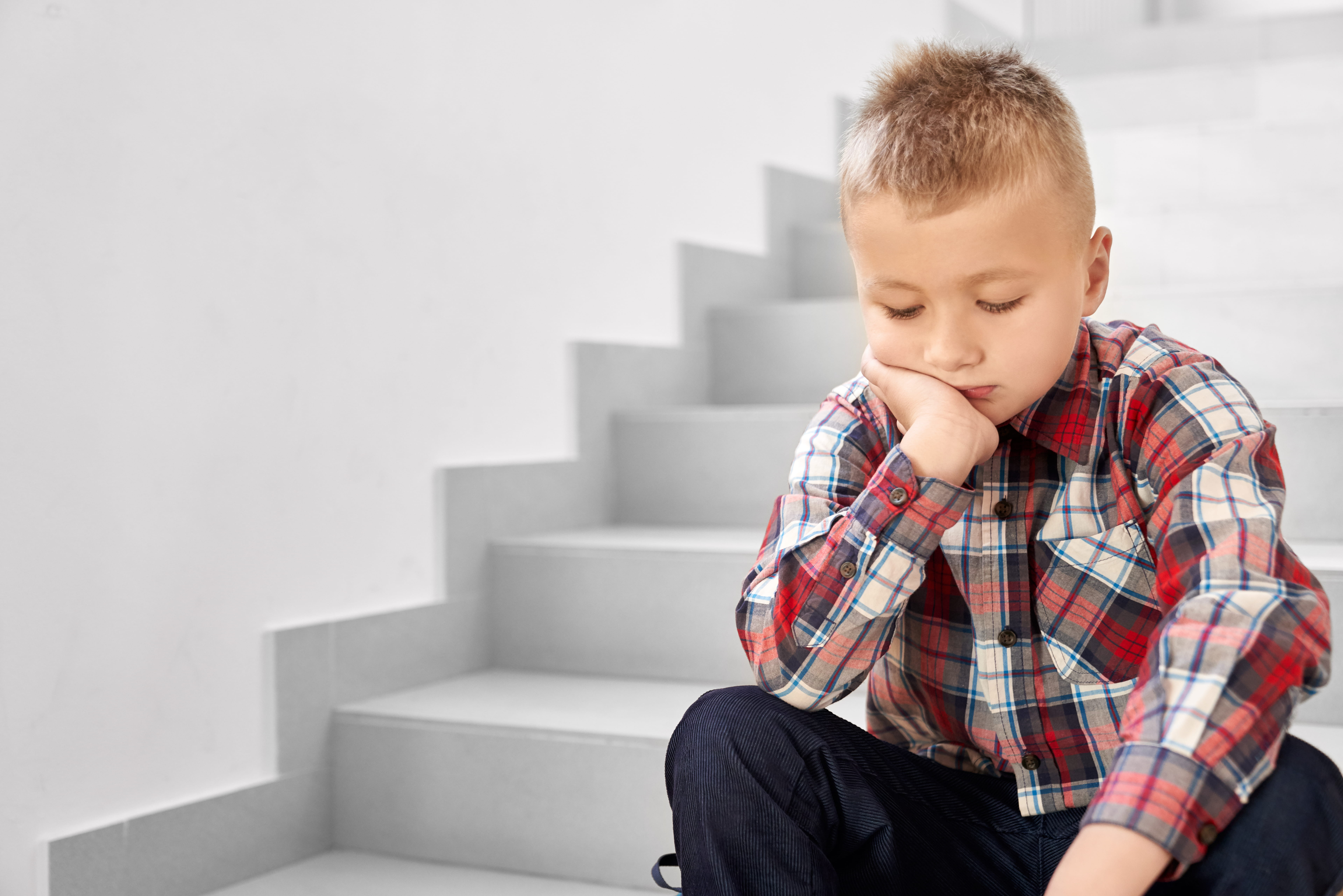 Boy looking down with chin resting on hand