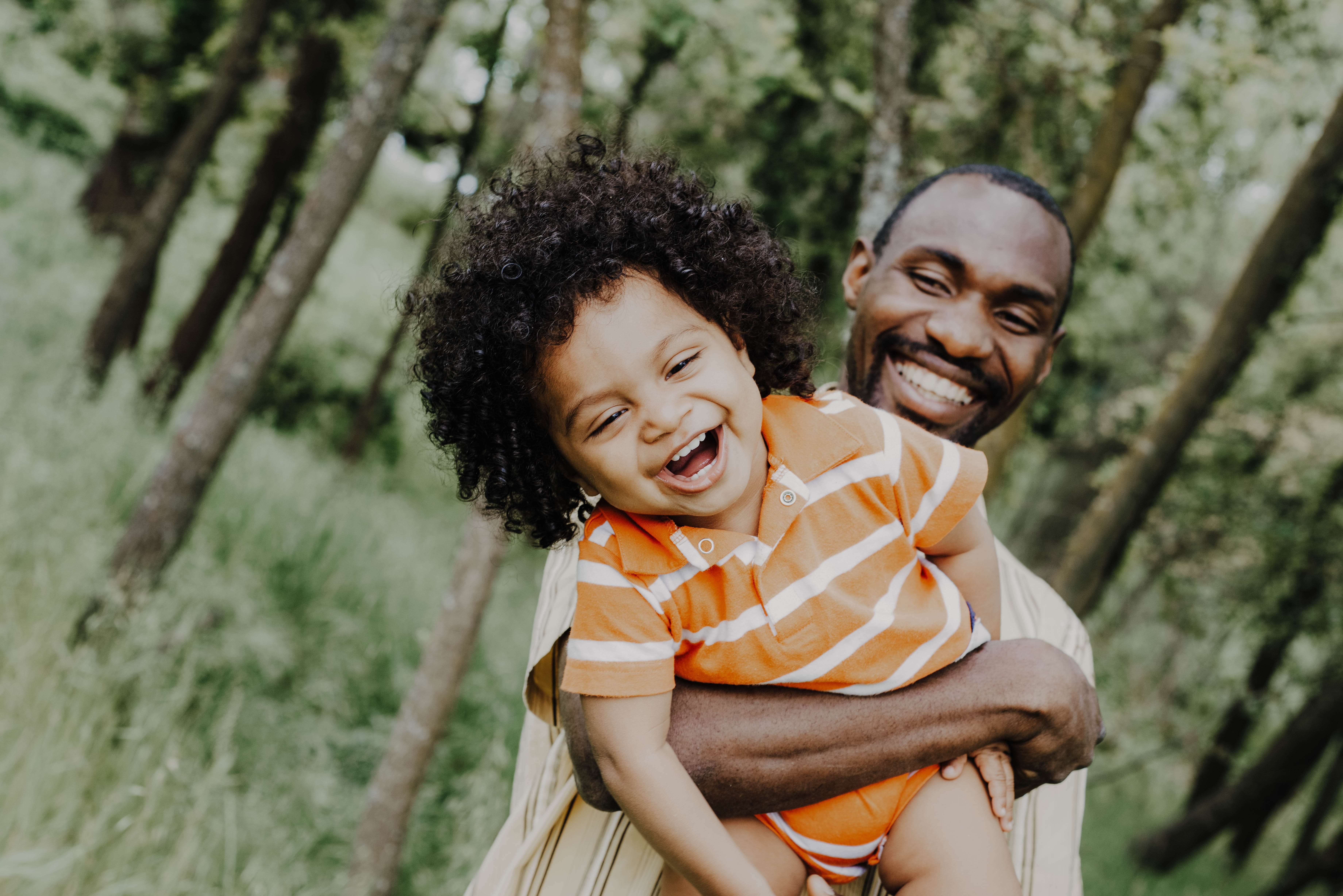 Photo of a laughing child being carried by his father.