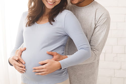 man with arms around pregnant women with hands on belly